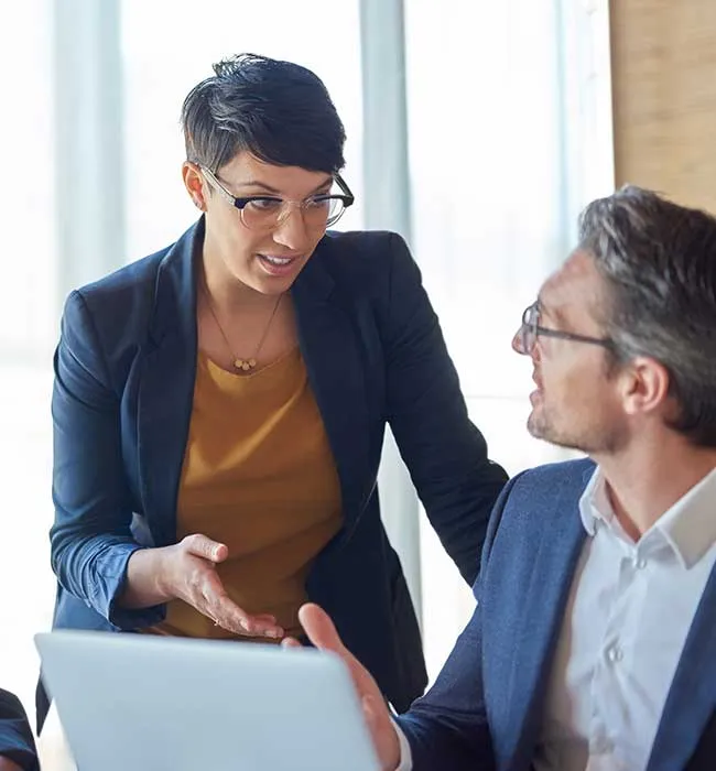 A woman and man in business attire looking at something on a laptop.